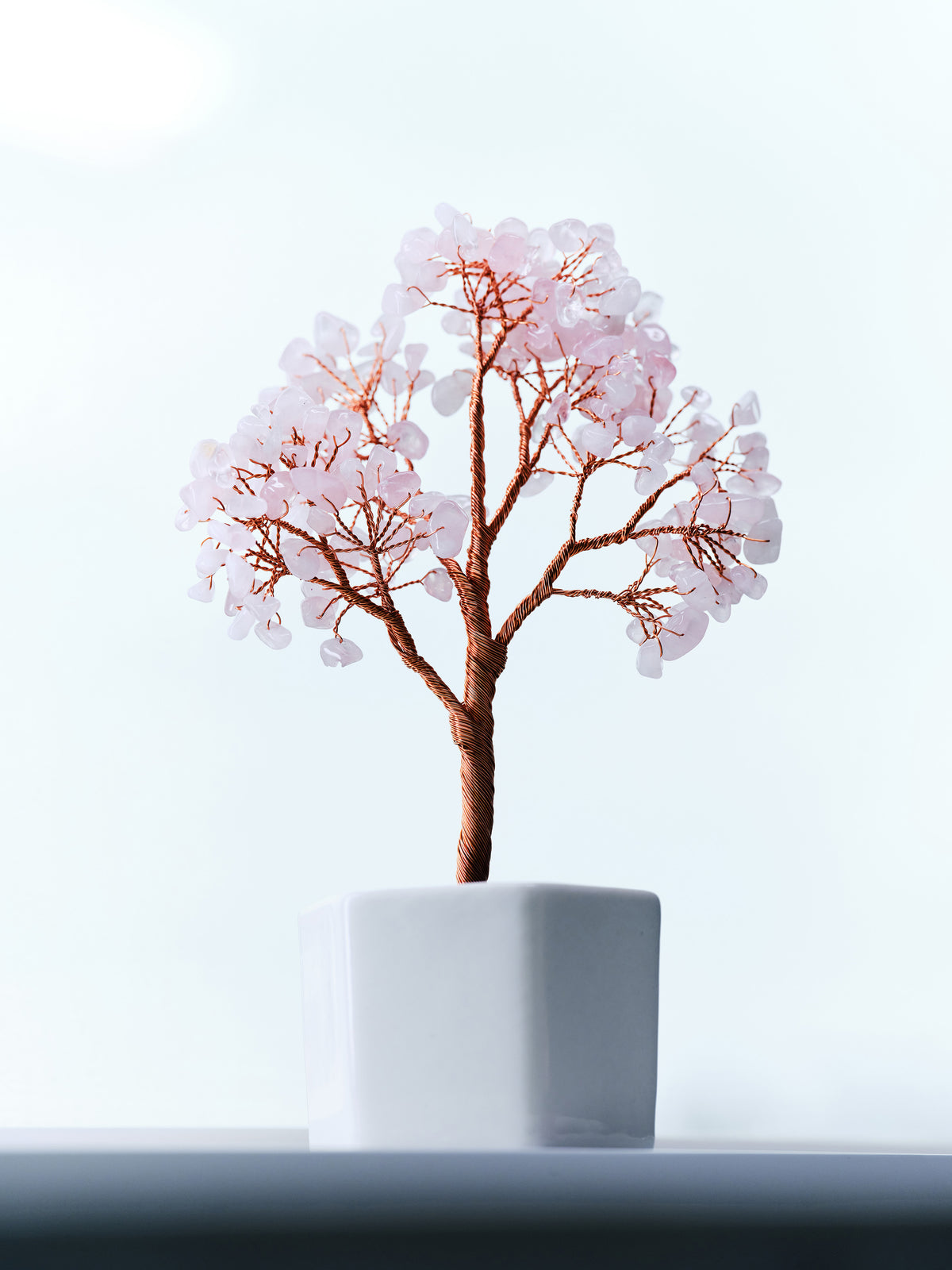 Soft Hold rose quartz crystal tree with copper wire branches in a white pot