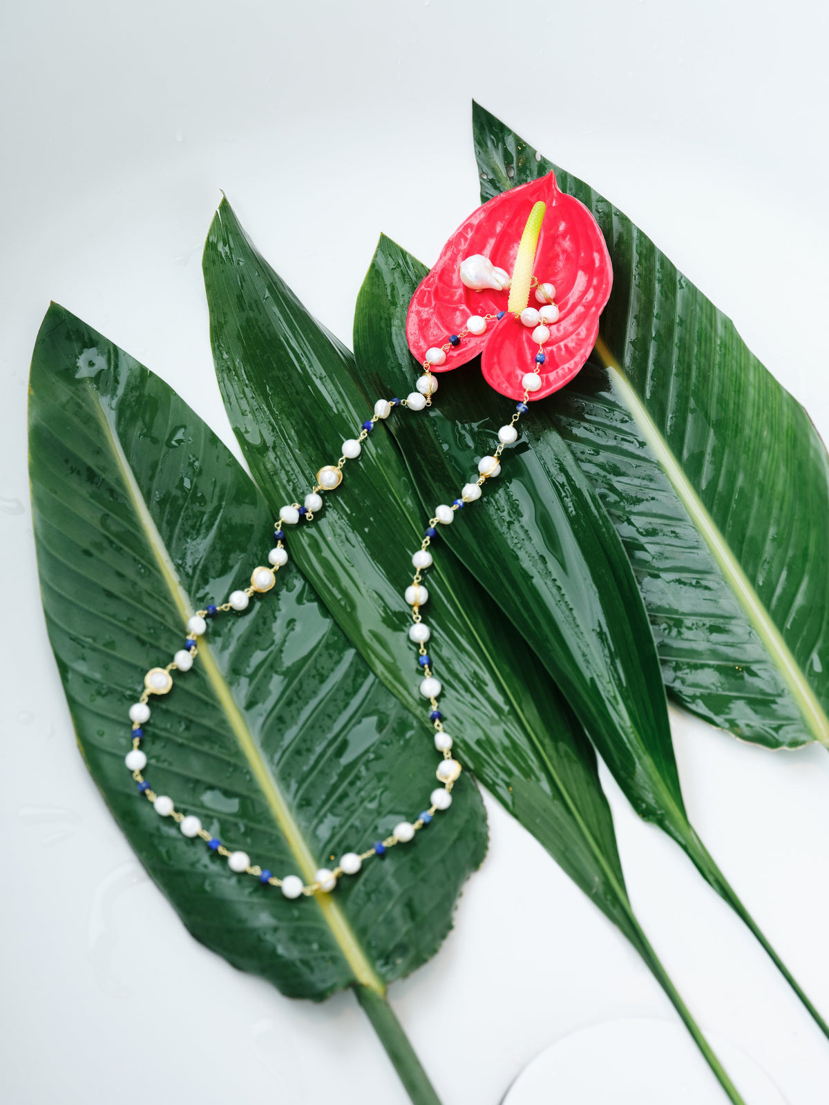 Chromatic Tide Pearl Necklace alternate styled view on layered green leaves