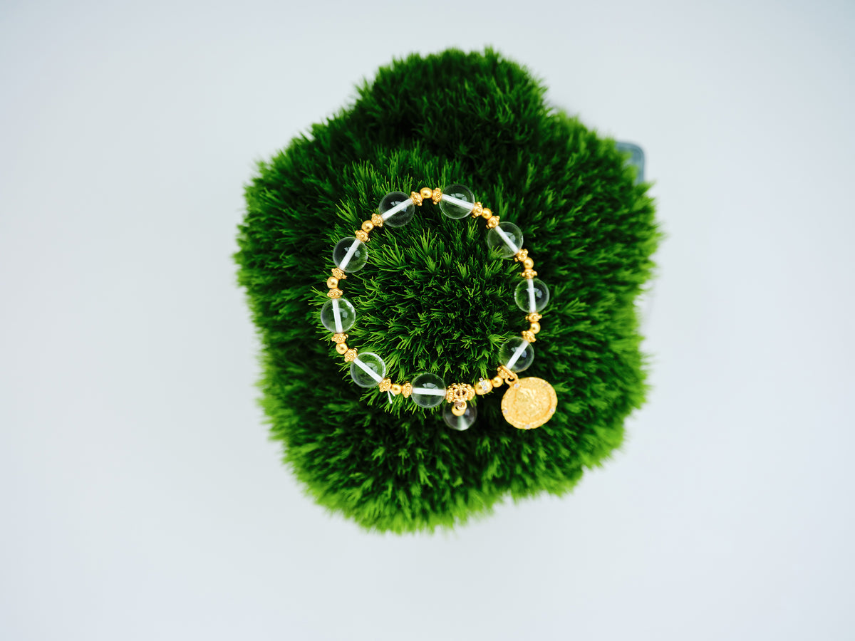 Coin Halo Bracelet with clear crystal beads and small 24K gold-plated copper coin accents on green moss.