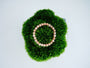 Golden Hour Bracelet with warm peach sunstone beads arranged in a circle on deep green moss
