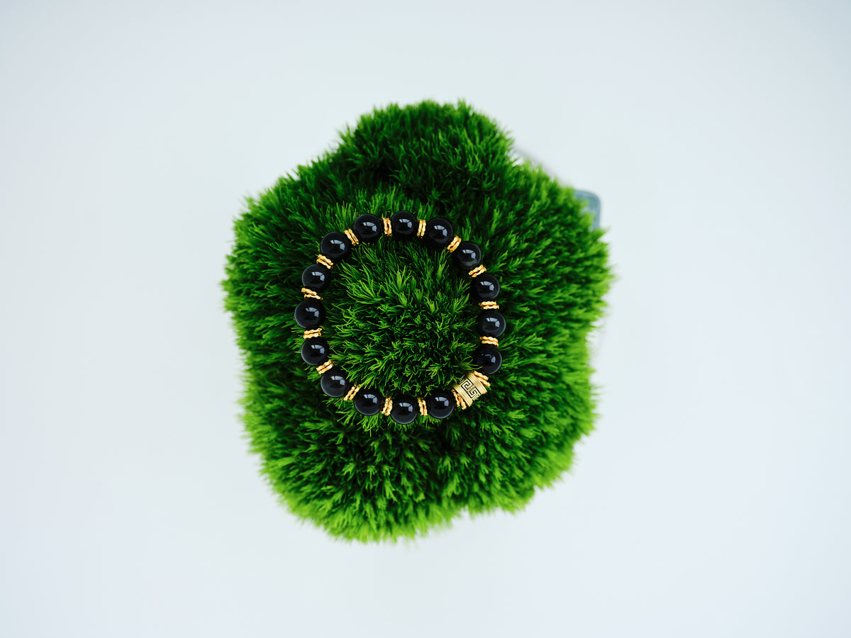 Midnight Orbit Bracelet with deep dark crystal beads and 24K gold-plated copper accents on green moss.