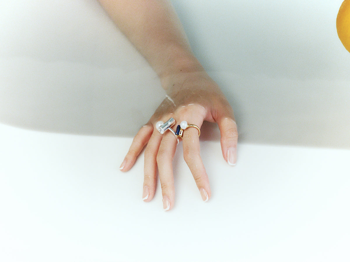 Layered pearl, lapis and silver-tone adjustable rings worn together on a hand