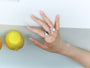 Three adjustable Aurasphere rings styled together on a hand beside a lemon