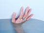 Adjustable pearl and gemstone rings styled on a hand against a pale blue water setting
