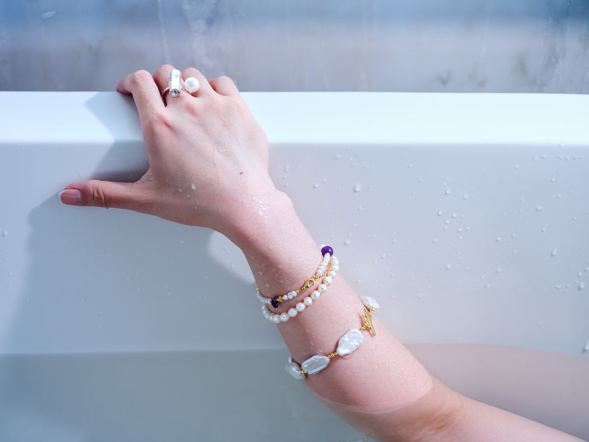 Silver-tone geometric bar and freshwater pearl adjustable ring worn with pearl bracelets