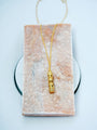 Gold-plated copper necklace with an ornate cylindrical pendant and clear crystal accents